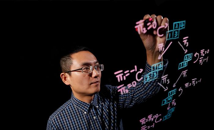 Professor Jia Juang writing equations on a marker board